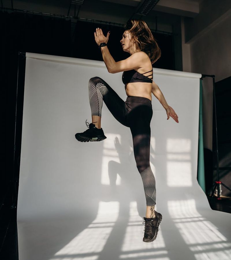 Woman in activewear performing a light cardio exercise indoors.
